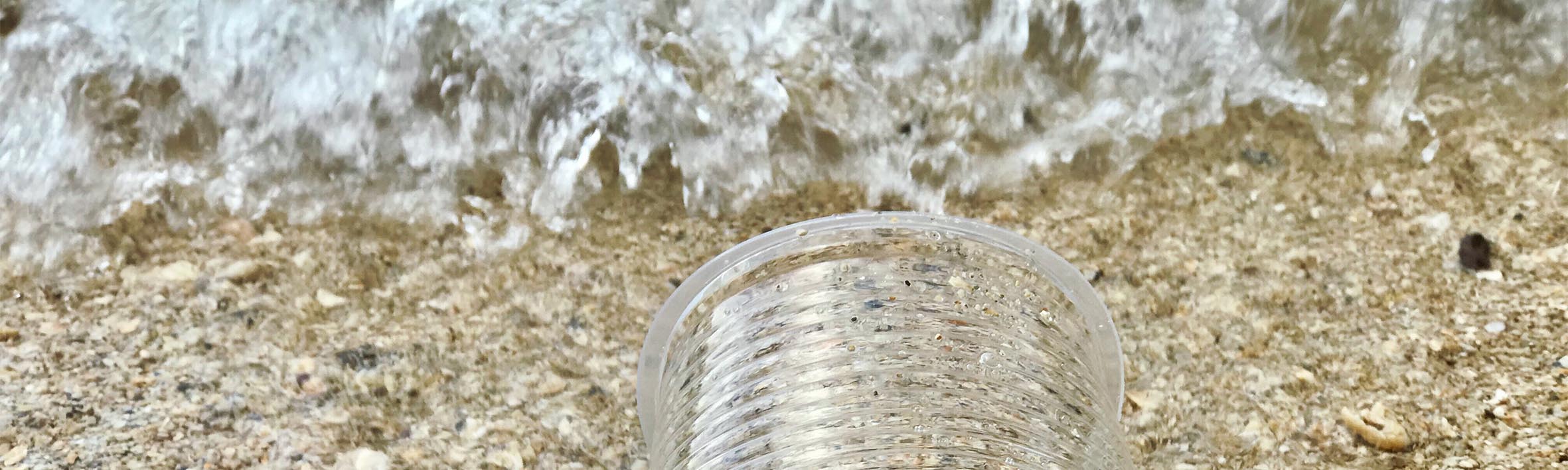 Vaso plástico de un solo uso en arena de playa